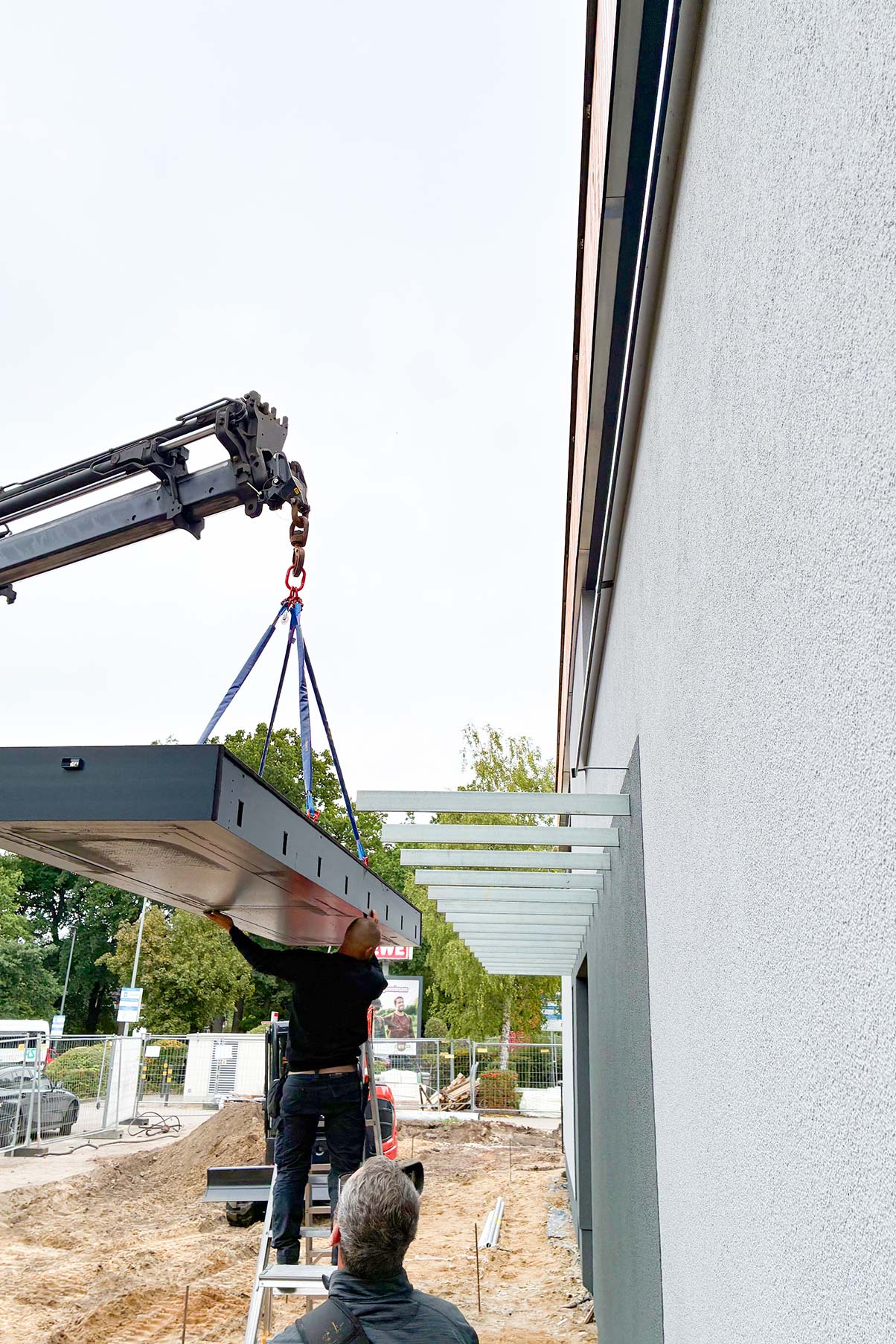 Vordach-Platin-auf-Tragwerk-wir-mit-Hilfe-eines-Krans-auf-die-Tragschwerter-geschoben